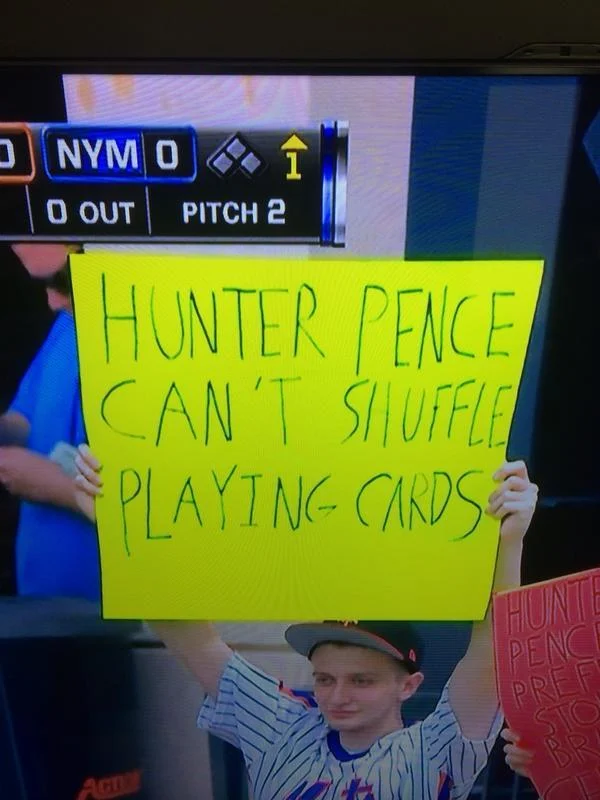 Hunter Pence Signs — TV broadcast showing young boy in Mets jersey holding yellow sign 'Can't Shuffle Playing Cards'.