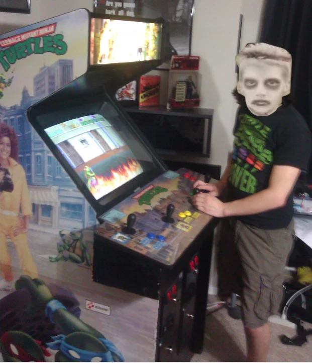 I Like Turtles — Person wearing zombie boy mask and TMNT shirt playing a Teenage Mutant Ninja Turtles arcade game