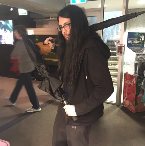 I Studied the Blade — Long-haired person posing with umbrella like a katana in Vancouver Aquarium