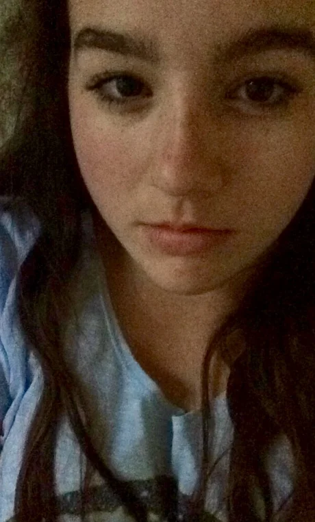 I Woke Up Like This — Grainy low-light selfie of a young woman with a neutral expression.