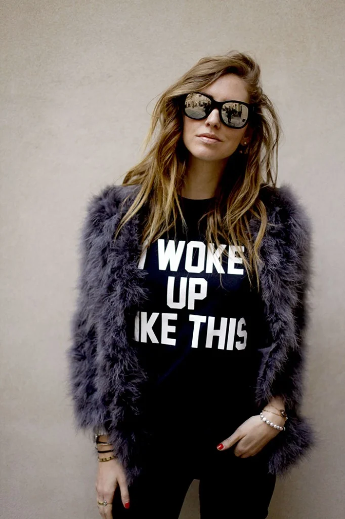 Woman in sunglasses and fur jacket wearing an 'I Woke Up Like This' slogan t-shirt.
