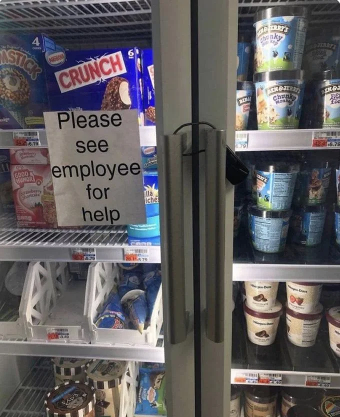 Ice Cream Challenge — Supermarket ice cream freezer with handwritten paper sign reading 'Please see employee for help' indicating locked access.