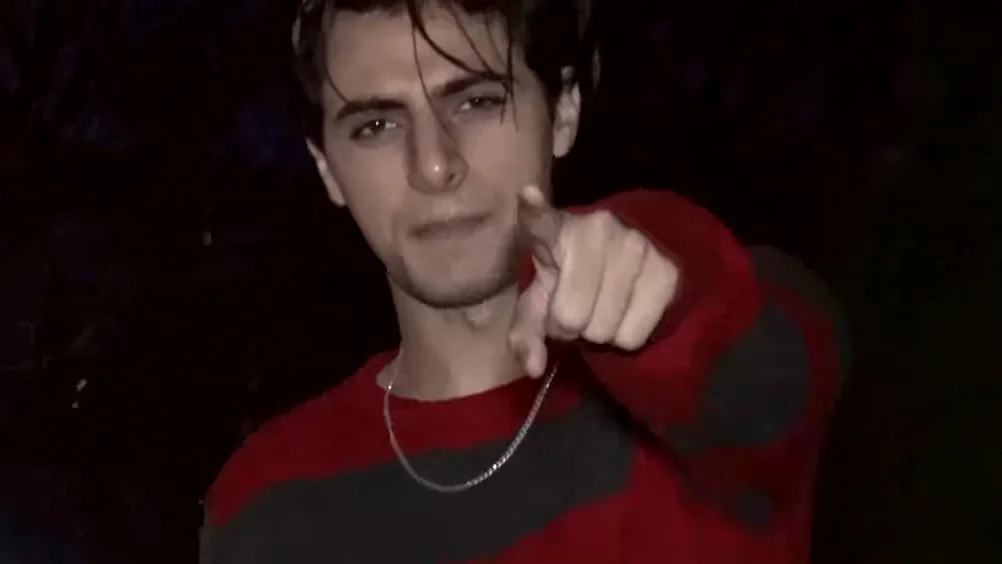 I'm Ethan Bradberry — Young man in red and black striped sweater pointing at camera at night