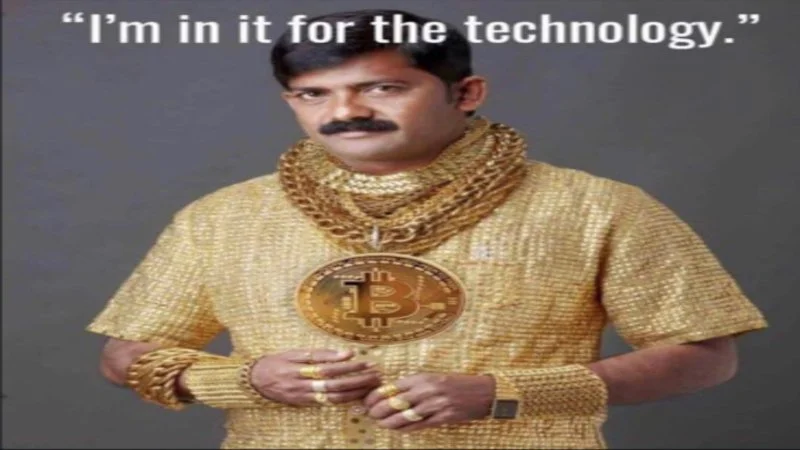 Man wearing gold shirt with large gold chains holding Bitcoin with text 'I'm in it for the technology' at top.