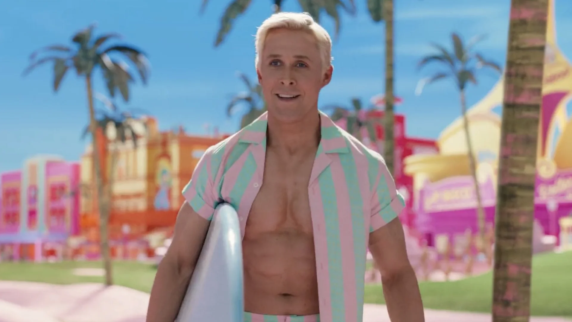 Im Just Ken — Ryan Gosling as Ken in a striped beach outfit holding a surfboard in Barbieland