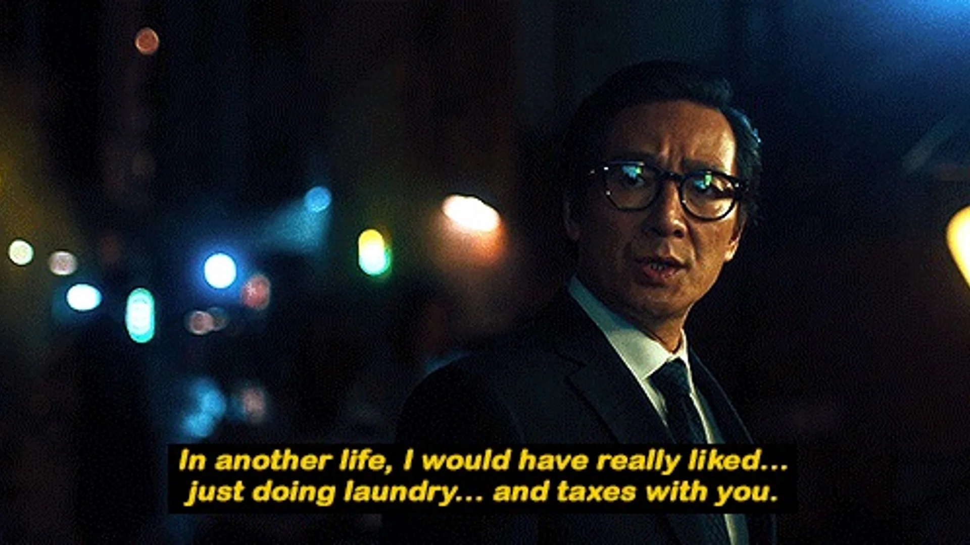 In Another Life, I Would Have Really Liked Just Doing Laundry and Taxes With You — Ke Huy Quan as Waymond Wang in a dark suit on a city street at night with