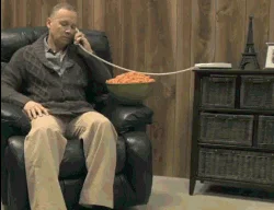 Infomercial Fails — GIF still showing man in recliner on phone with orange snack food connected by cord across frame.