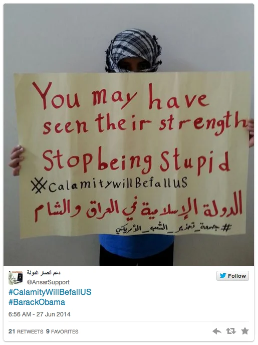 Masked ISIS supporter holding threatening handwritten sign in tweet screenshot