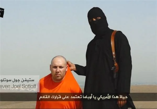 Still from ISIS video showing captive journalist Steven Sotloff next to masked militant