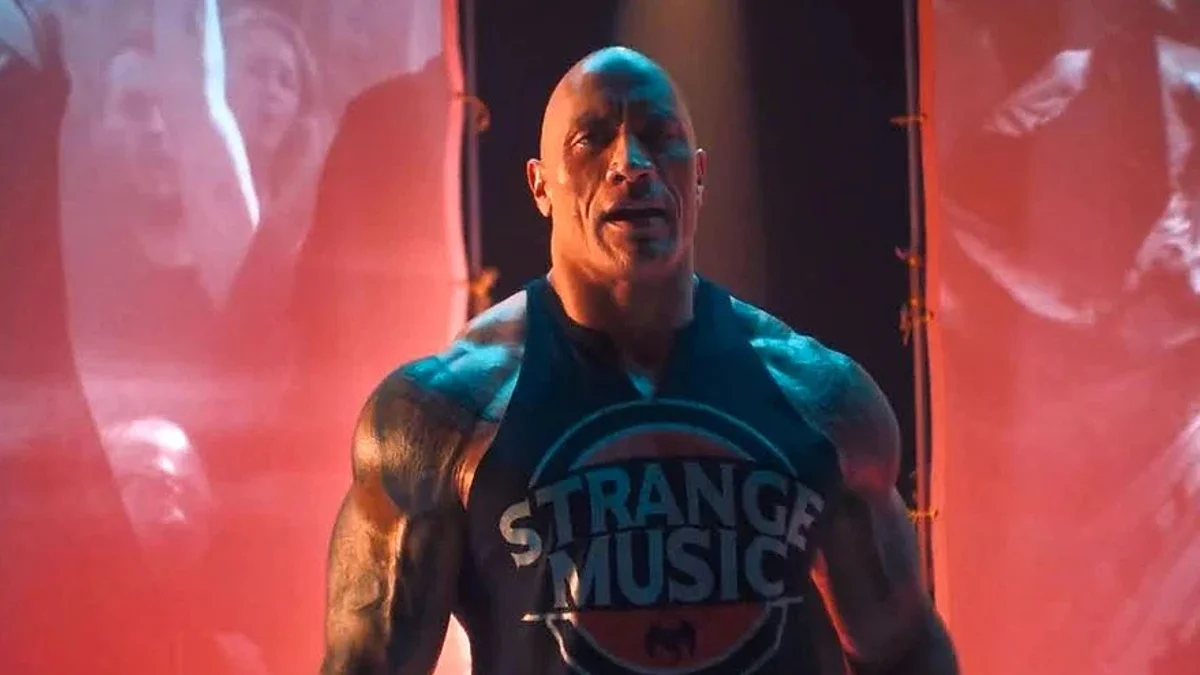 It's About Drive, It's About Power — Dwayne Johnson in a black Strange Music tank top rapping on stage with red lighting behind him