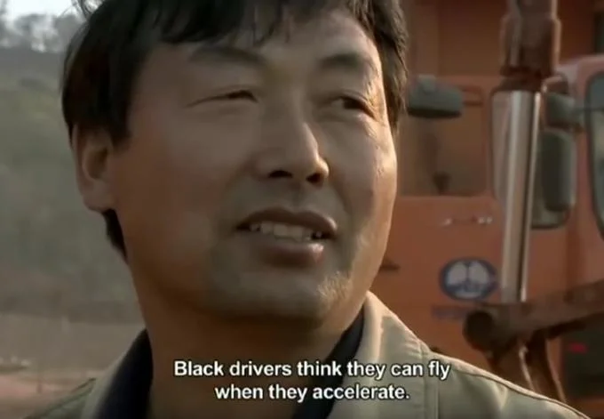 It's All So Tiresome — Documentary still of smiling Chinese worker with racially charged subtitle about truck drivers.