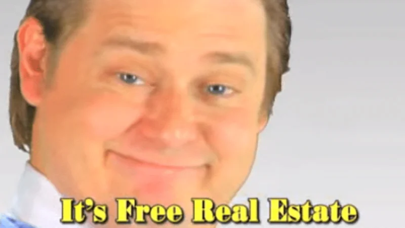 Smiling man with slicked-back hair beside yellow 'It's Free Real Estate' caption