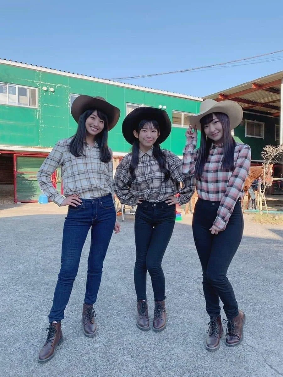 Three Japanese women dressed in cowgirl outfits posing outdoors