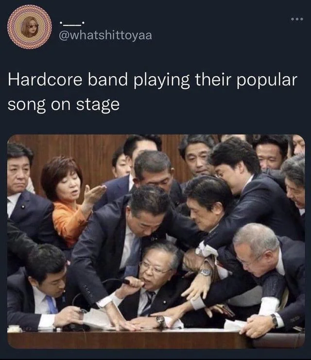 Japanese Parliament Trying To Stop Shinichi Yokoyama — Tweet from @whatshittoyaa captioning the parliament scrum as a hardcore band on stage