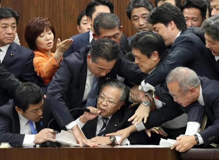 Japanese Parliament Trying To Stop Shinichi Yokoyama — Close crop of Shinichi Yokoyama holding microphone while politicians grab at him