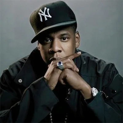 Jay Z — Jay-Z posing in black jacket and NY Yankees cap with hands clasped