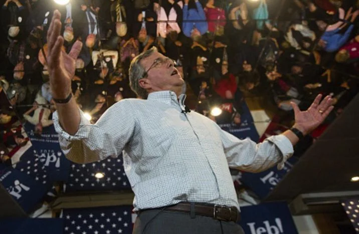 Jeb Wins — Jeb Bush standing at a campaign rally with arms spread wide and head tilted back.