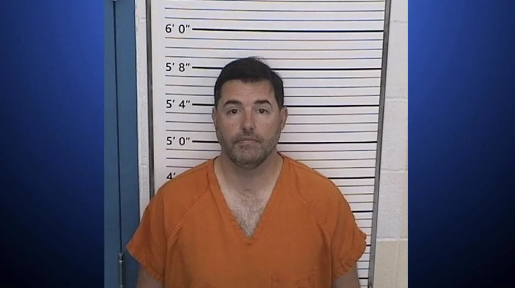 Jed York Prostitution Arrest — Mugshot of a bearded man in an orange jail jumpsuit standing against a height chart