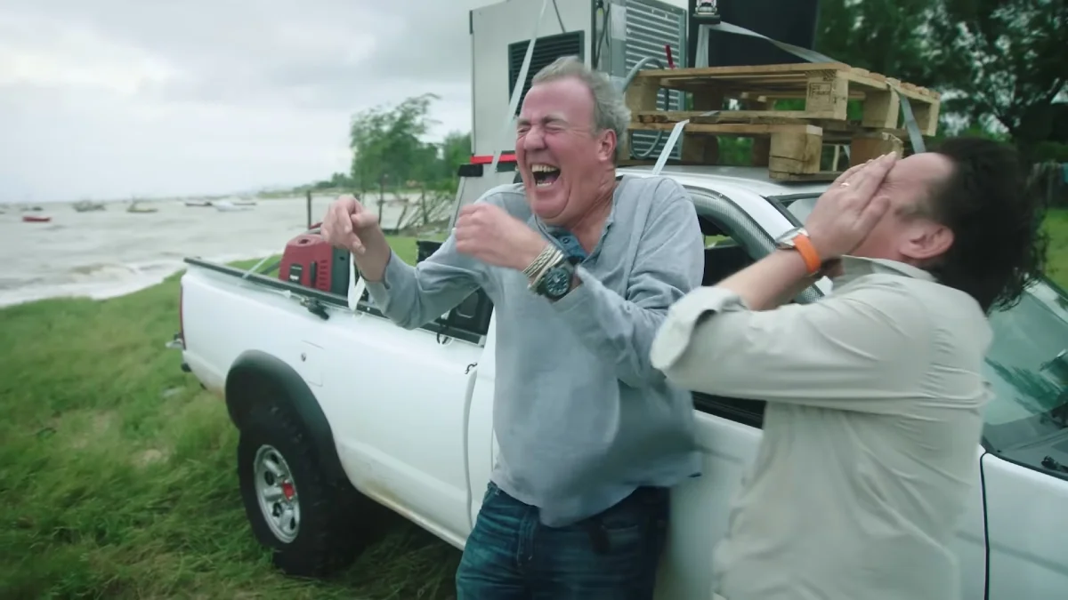 Jeremy Clarkson and Richard Hammond Laughing In the Wind — Jeremy Clarkson laughing openly next to Richard Hammond who covers his face, beside a white pickup