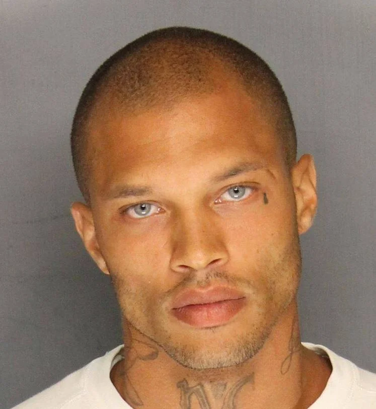 Jeremy Meeks' Mugshot — Jeremy Meeks mugshot showing his face with blue eyes and neck tattoos against a gray background.