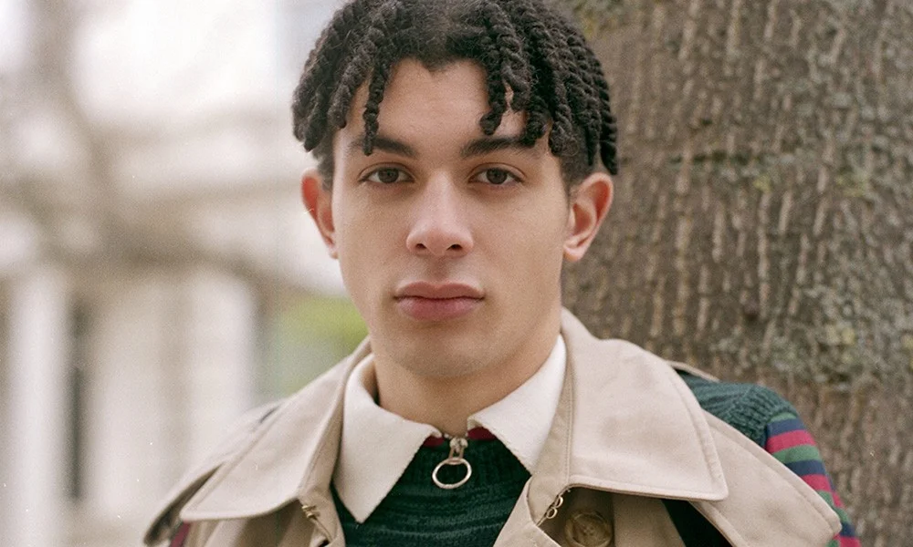 Portrait of rapper Jimothy Lacoste in a beige trench coat outdoors