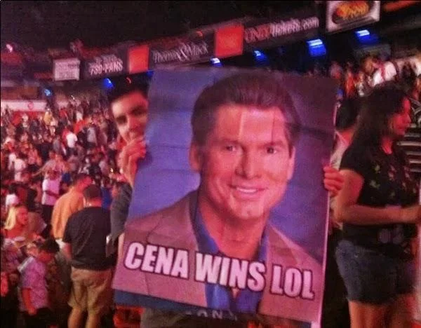 John Cena Prank Call — A crowd at a WWE wrestling event with someone holding a sign reading 'CENA WINS LOL.'