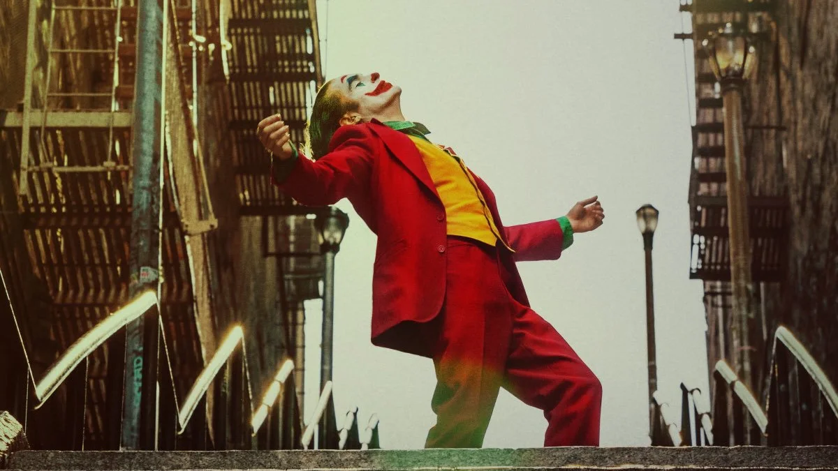 Joker (2019 Film) — Joaquin Phoenix as Joker in red suit dancing on stairs