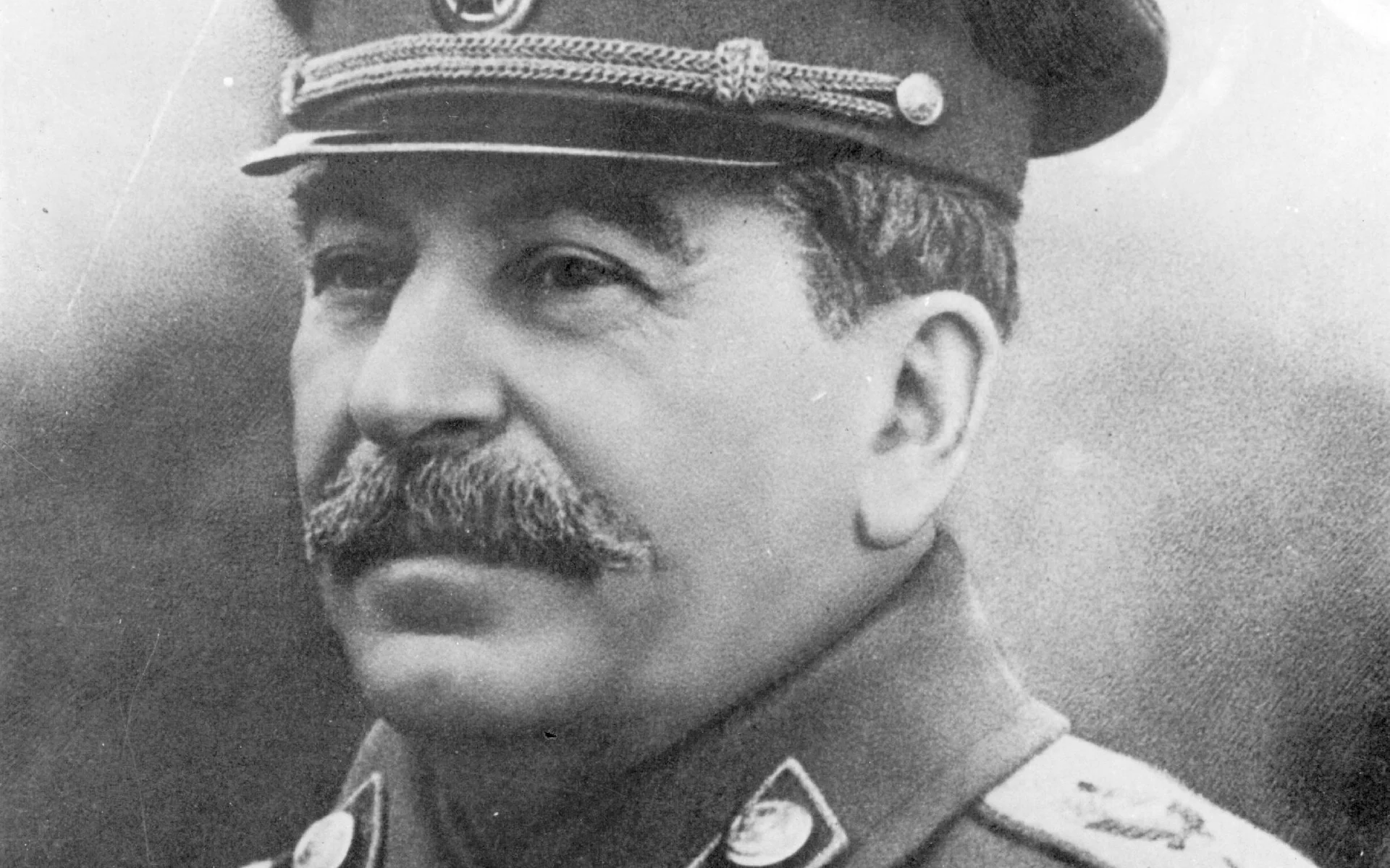Black-and-white portrait of Joseph Stalin in Soviet military uniform and cap.