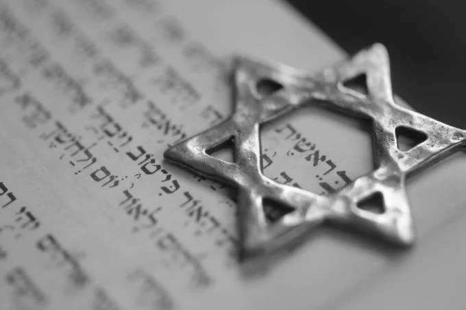 Judaism — Silver Star of David pendant lying on Hebrew scripture pages