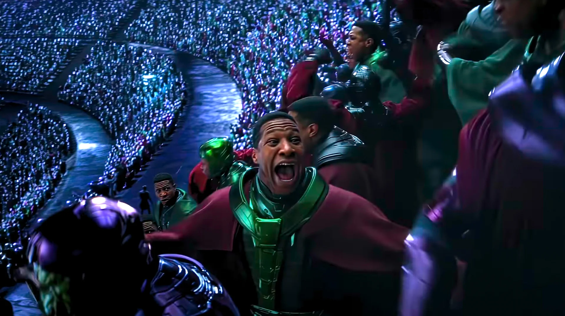 Kang Council Cheering — Jonathan Majors as Kang shouting in triumph in front of a massive stadium filled with cheering Kang variants from the Council of Kangs