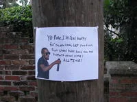 Handmade street sign displaying Kanye Interrupting meme text on utility pole