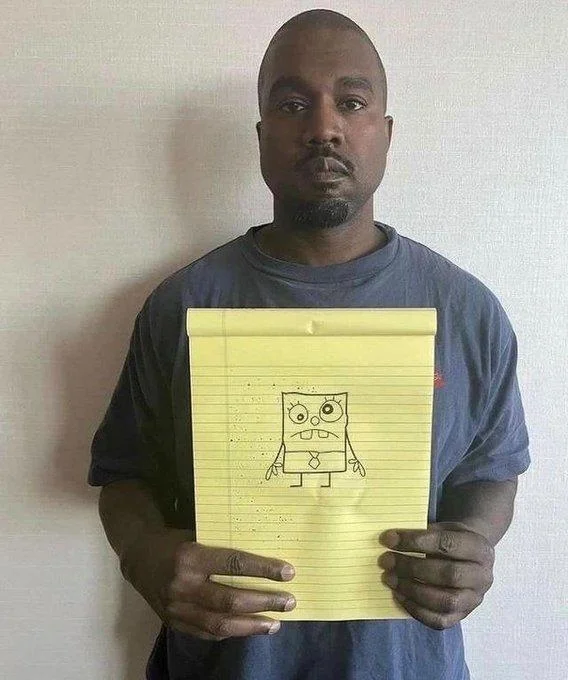 Kanye West Holding Notepad — Kanye West holding yellow legal pad with hand-drawn SpongeBob SquarePants sketch on notepad.