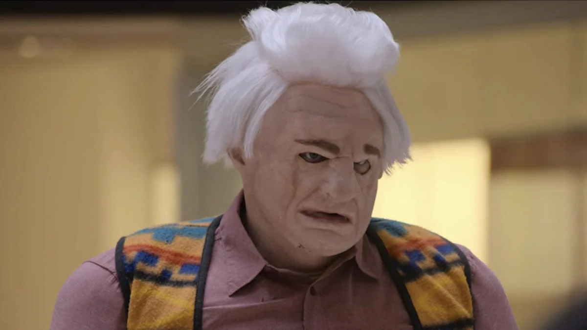 Tim Robinson in Karl Havoc old-man mask and white wig looking distressed