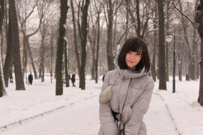 Katya Lischina in grey winter coat standing in snowy park