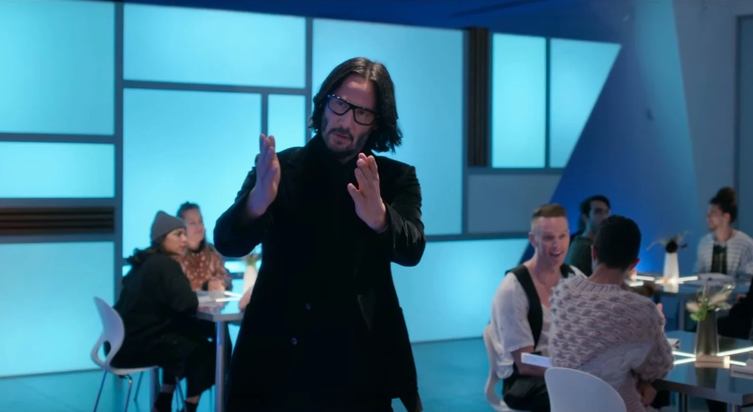 Keanu Reeves Walking in Slow Motion — Keanu Reeves walking through a blue-lit restaurant with hands raised in slow motion