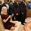 Kellyanne Conways Oval Office Couch Photo — Close-cropped version showing Kellyanne Conway in burgundy dress kneeling on beige Oval Office sofa checking phone.