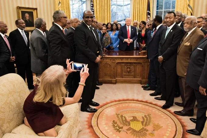 Kellyanne Conways Oval Office Couch Photo — Wide-angle press photo showing Kellyanne Conway kneeling on Oval Office sofa checking her phone while HBCU