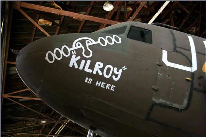 Kilroy Was Here — Photograph of military aircraft nose art showing Kilroy with 'Kilroy Is Here' in white paint.