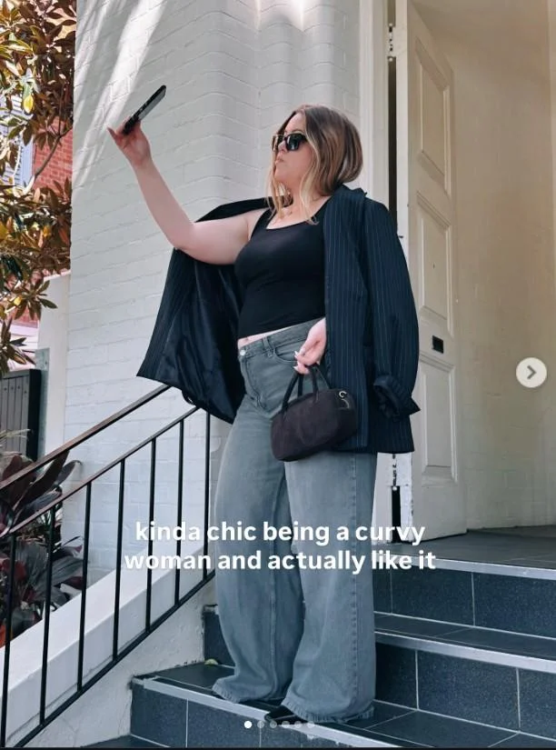Kinda Chic Trend — Woman in blazer and wide-leg jeans posing on stairs with text 'kinda chic being a curvy woman and actually like it'.