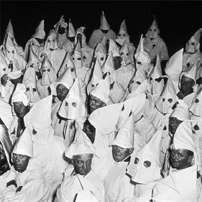 Vintage black-and-white photo of a crowd of people in white Ku Klux Klan robes and pointed hoods