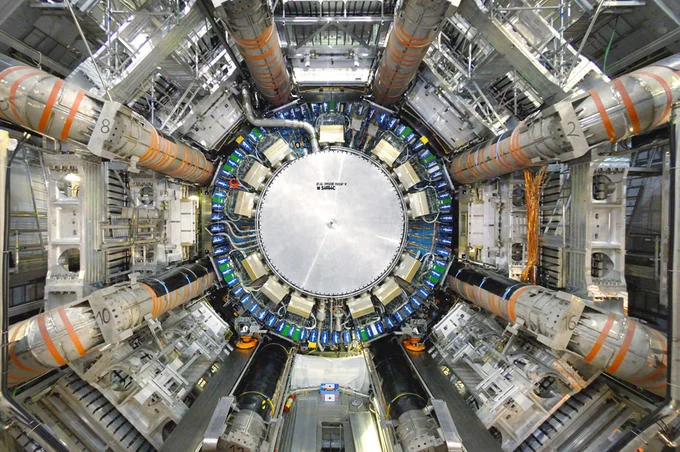 Interior view of the Large Hadron Collider detector with circular metal panels glowing in orange and blue.