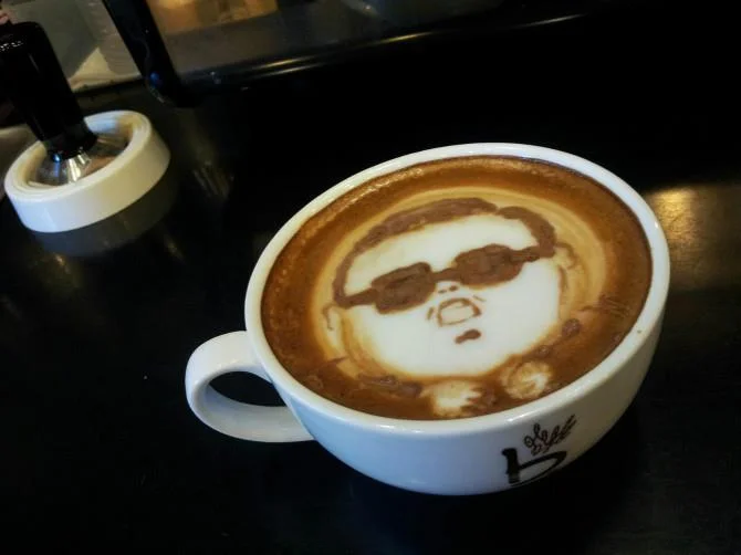 Latte art portrait of Psy from Gangnam Style wearing dark sunglasses.
