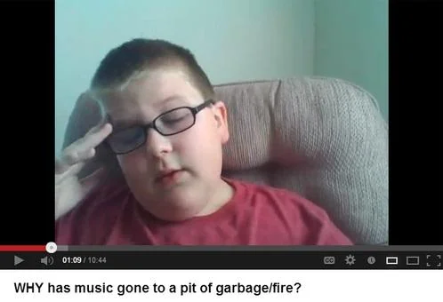 Le Wrong Generation — A screenshot of a YouTube video showing a young boy in a red shirt with glasses pressing his finger to his temple in a frustrated