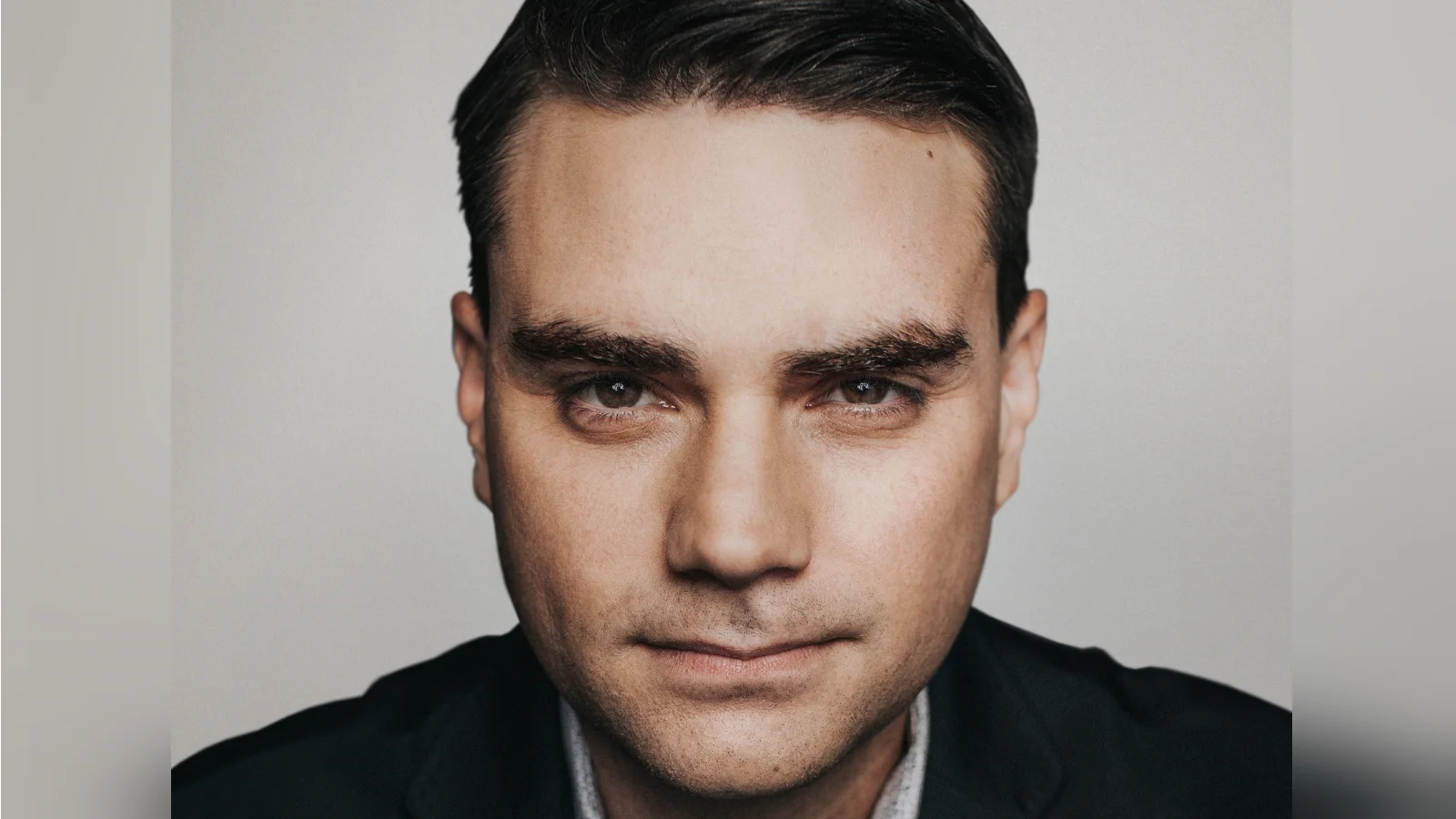 Let's Say, Hypothetically — Close-up portrait of Ben Shapiro in a dark blazer against a grey background.