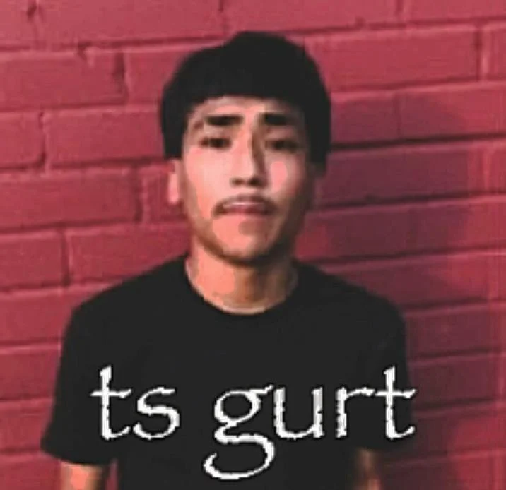 Lil G Photo Houston Resident — Lil G stands against the red brick wall in his signature black shirt and Edgar haircut, with a simple text caption 'ts gurt' at