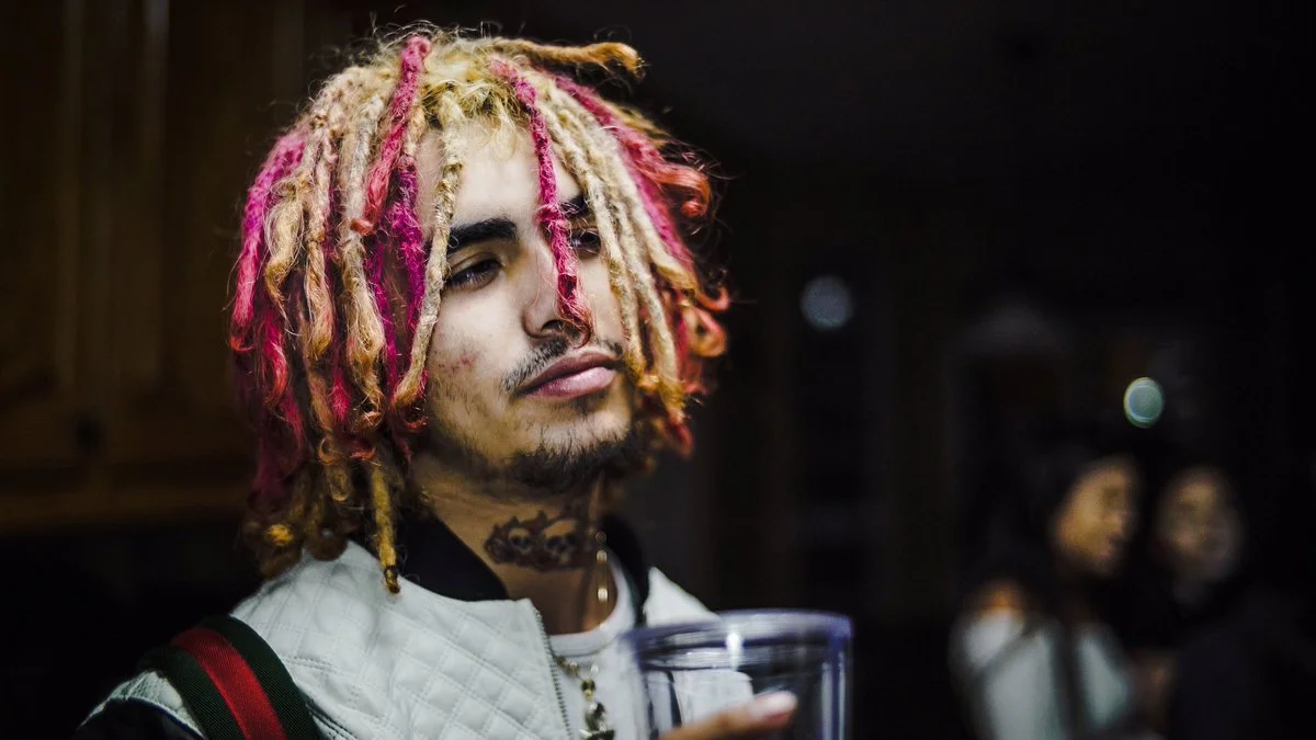Rapper Lil Pump with pink and blonde dreadlocks holding a plastic cup