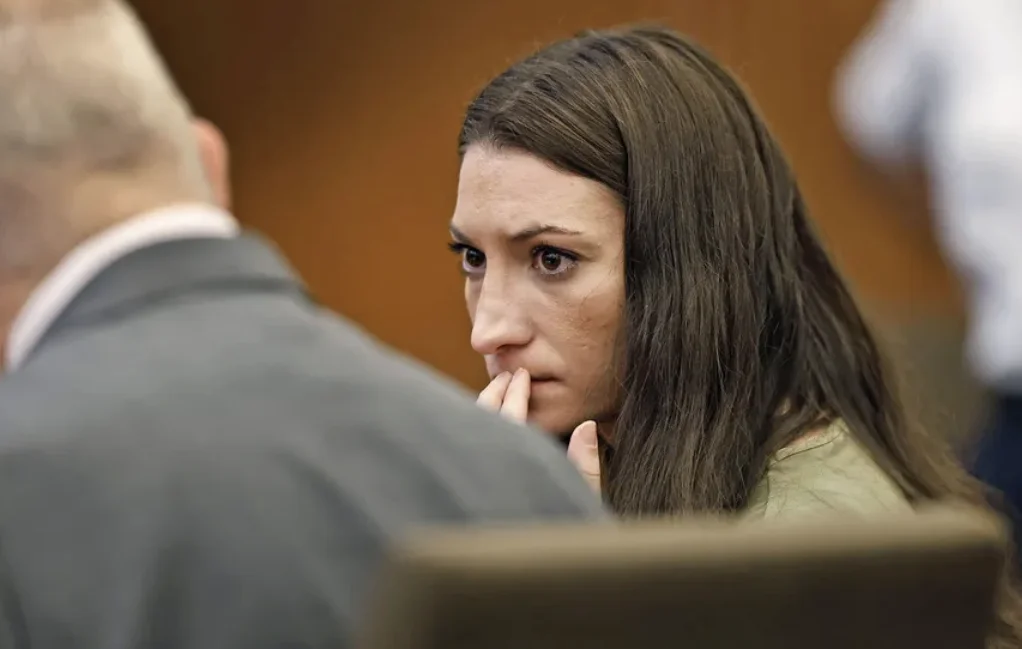 Lindsay Clancy Trial — Lindsay Clancy in court with her hand near her mouth, looking at a man in a suit.