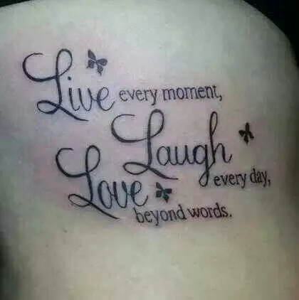 Live Laugh Love — A tattoo on skin displaying 'Live every moment, Laugh, Love every day, beyond words' with decorative butterfly and floral elements.