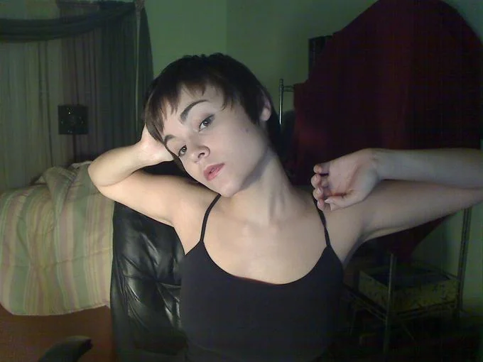 Loli-chan — Young woman with short dark hair posing in black tank top in bedroom