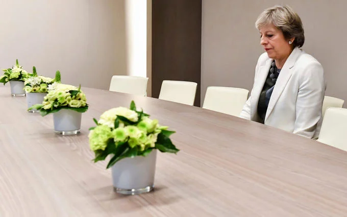 Lonely Theresa May — Wider view of Theresa May sitting alone at an empty conference table.